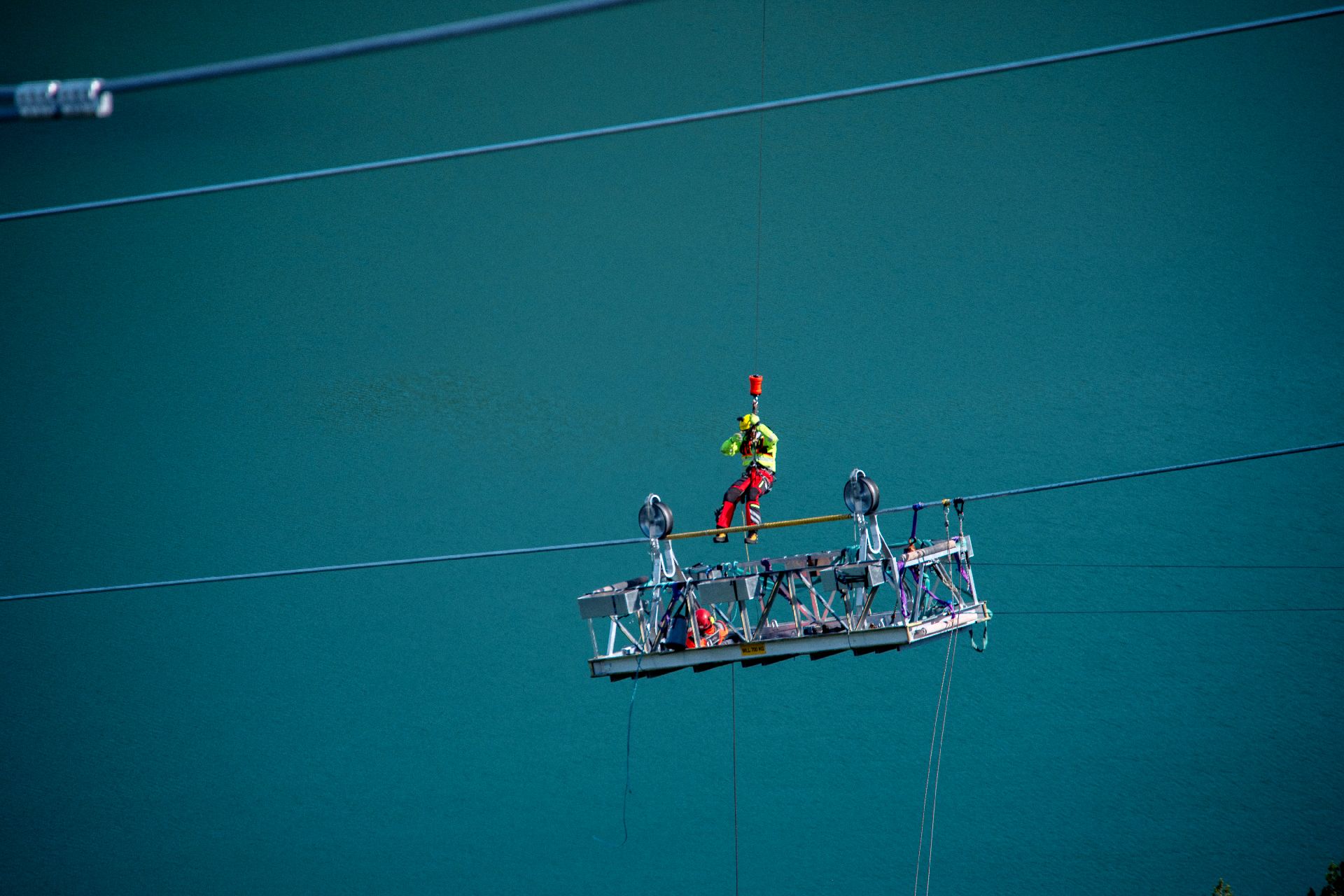 Rescuer on a hoist line above a work platform on a cable span